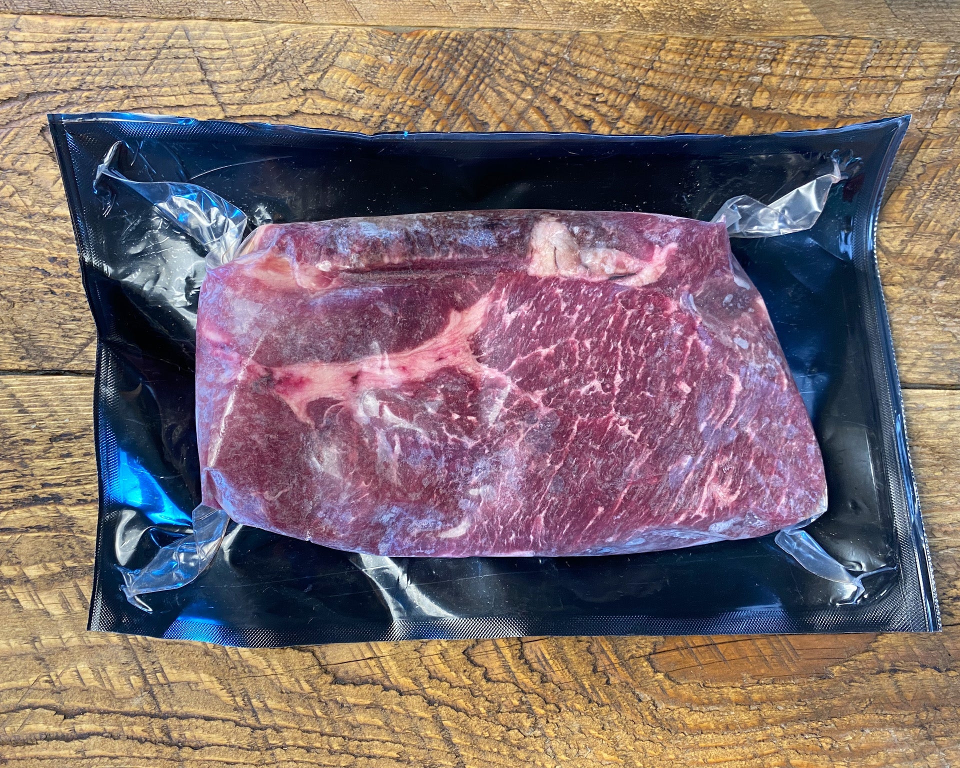 Boneless chuck steak in vacuum packaging, showcasing grass fed beef ready for cooking or grilling.
